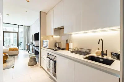 a white kitchen with a sink and a counter at Deluxe Studio Business Bay - Balcony City Skyline Views in Dubai