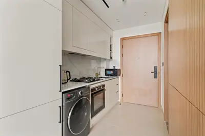 a kitchen with a stove and a dishwasher at Modern Studio with Pool & Gym - Prime JVC Location in Dubai