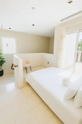 a white bedroom with a large bed and a desk at Family Villa, Sleeps up to 9 in JVT and Large garden in Dubai