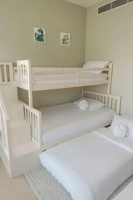 two bunk beds in a room with white walls at Family Villa, Sleeps up to 9 in JVT and Large garden in Dubai