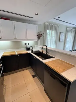 a kitchen with black and white cabinets and a sink at Family Villa, Sleeps up to 9 in JVT and Large garden in Dubai