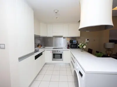 a kitchen with white cabinets and white appliances at Emaar Residenc Fashion Avenue - Sokoon in Dubai