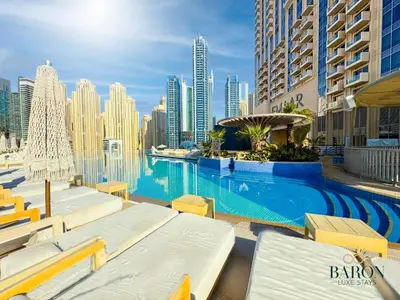 a swimming pool with lounge chairs and a city skyline at The Majestic in Dubai