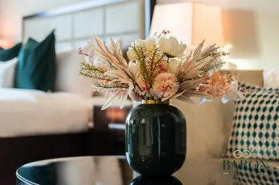 a green vase filled with flowers on a table at The Glamorous in Dubai