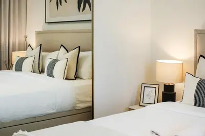 two beds in a bedroom with a mirror at Stylish 4BD Villa Opposite Pool & Park in Dubai