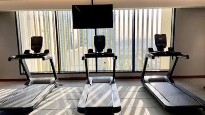 a gym with three treadmills in front of a window at Chic Urban Escape Sobha Crest 1BR with Private Balcony in Dubai