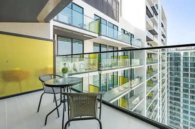 a balcony with a table and chairs and a building at Near Gadaf Community Park, Few Minutes Walk to Circle Mall, Short Drive to Dubai Miracle Garden and Butterfly Garden - Binghatti Amber, JVC by Deluxe Holiday Homes in Dubai