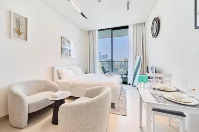 a hotel room with a bed and a table and chairs at FAM Living Stylish Studio Apartment in Binghatti Azure JVC in Dubai