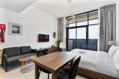 a living room with a bed and a dining table at Modern Studio with City Views Near Miracle Garden in Dubai