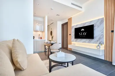a living room with a couch and a tv on a wall at STAY BY LATINEM Luxury 1BR Holiday Home CB 3113 Near Burj Khalifa in Dubai