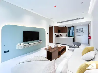 a living room with a couch and a tv on a wall at Exclusive 1BR, Modern Comfort & Prime Location in Dubai