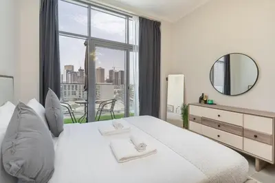 a bedroom with a large white bed with a large window at Modern 1BHK Apartment in Pantheon JVC by Czechin in Dubai