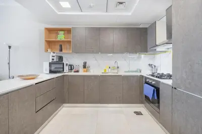 a kitchen with white counters and brown cabinets at Modern 1BHK Apartment in Pantheon JVC by Czechin in Dubai