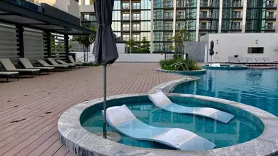 a swimming pool with an umbrella in a building at Elegant 1BR with Bedroom Balcony - Sobha Crest C in Dubai