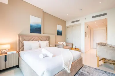 a bedroom with a large white bed and a chair at Upgraded LUX Infinity Pool with Beach Access in Dubai