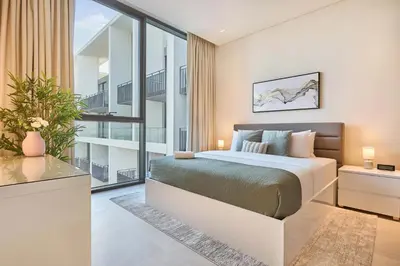 a bedroom with a king sized bed and a balcony at Elegant Apartment near Miracle Garden with Pool & Gym Access in Dubai