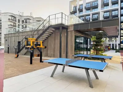 two ping pong tables in front of a building at Elegant Apartment near Miracle Garden with Pool & Gym Access in Dubai
