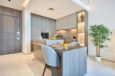 a kitchen with a island with a table and chairs at Elegant Apartment near Miracle Garden with Pool & Gym Access in Dubai