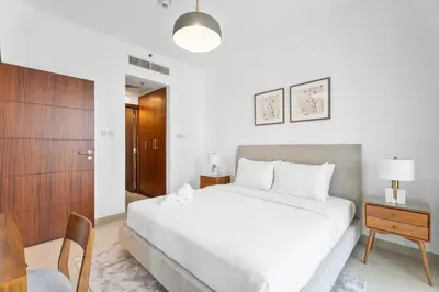 a bedroom with a white bed and a wooden cabinet at Boema Apartments - Terrace with Stunning Burj View in Dubai