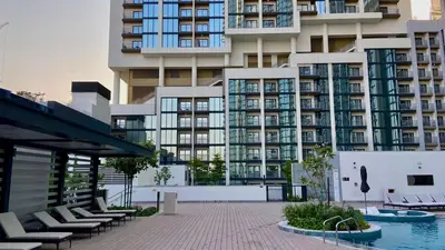 a large apartment building with chairs and a swimming pool at Premium Stay in Sobha 1BR with Extra Room and Balcony in Dubai
