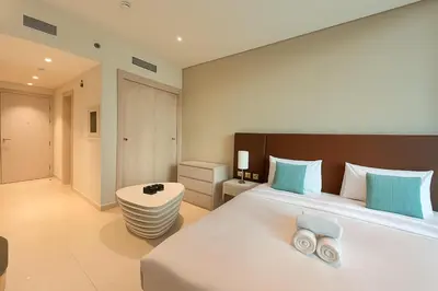 a bedroom with a large white bed with blue pillows at LUX Infinity Pool with GYM, Private Beach Studio in Dubai