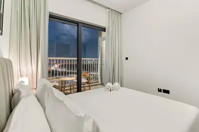 a bedroom with a white bed and a balcony at FIRST CLASS 2BR Bright and Elegant Living in Dubai