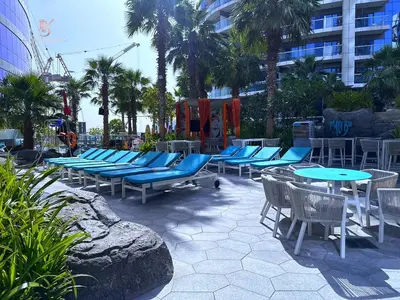 a row of chairs and tables with blue chairs and palm trees at Your Hollywood-Style Hideaway -DAMAC Paramount in Dubai