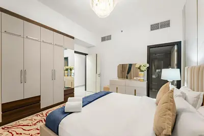a white bedroom with a large bed and a chandelier at FIRST CLASS 2BR Chic Getaway Close to Metro in Dubai