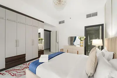 a white bedroom with a large bed and a chandelier at FIRST CLASS 2BR Chic Getaway Close to Metro in Dubai