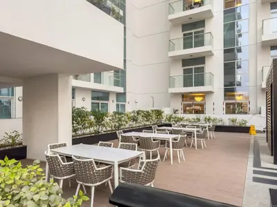 an outdoor patio with tables and chairs in a building at FIRST CLASS 2BR Chic Getaway Close to Metro in Dubai