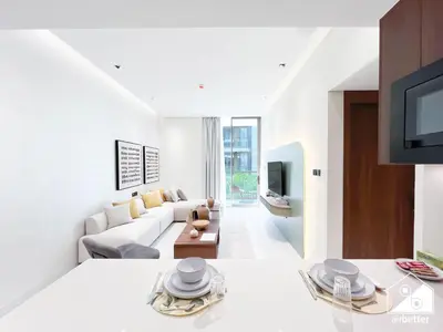 a white living room with a couch and a tv at Spacious 1-BR with Balcony & Leisure Facilities in Dubai
