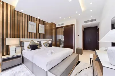 a bedroom with a large white bed and a desk at FAM Living Elite Residence 1BR Walk to JBR Beach in Dubai