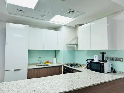 a kitchen with white cabinets and a black microwave at Stylish One Bed Apartment near Downtown in Dubai
