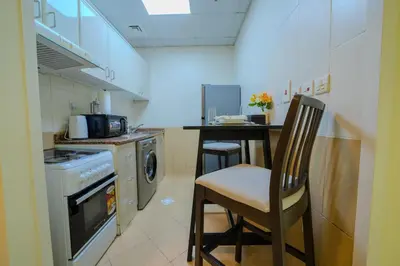 a kitchen with a counter and a table and chairs at Metrofront Stay - Walk to Iconic Dubai Spots in Dubai