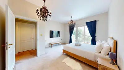 a bedroom with a large bed and a chandelier at Vacationer l Family Villa with Private Pool, Private Garden in Dubai
