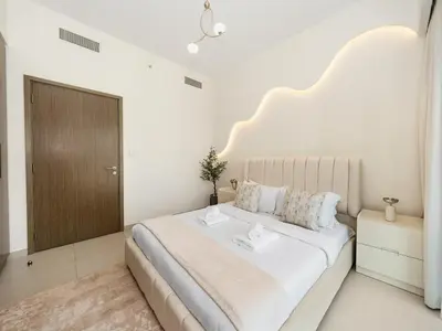 a white bedroom with a large bed with a large headboard at Luxury 2BR- Pool with Burj View- 5 Min to Dubai Mall in Dubai
