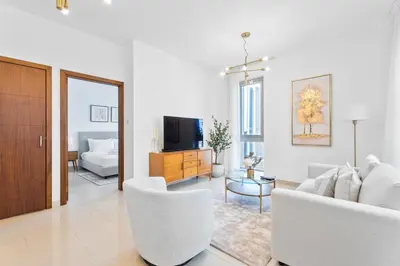 a living room with white furniture and a tv at Boema Apartments - Luxury with Burj Khalifa View in Dubai