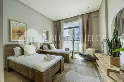 a living room with two beds and a large window at Bloomfields Marquis 2020 in Arjan in Dubai