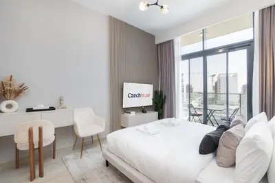 a white bedroom with a bed and a desk with a computer at Downtown-Close Studio by Czech-In in Dubai