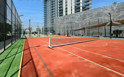 a tennis court with a net in a building at Vogue Al Maktoum City, District One Residence, within a short drive from Downtown Burj Khalifa and Dubai Mall, Three Bedroom Apartment plus Kids Room with Large Balcony in Dubai
