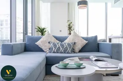 a blue couch in a living room with a table at Vogue Al Maktoum City, District One Residence, within a short drive from Downtown Burj Khalifa and Dubai Mall, Three Bedroom Apartment plus Kids Room with Large Balcony in Dubai
