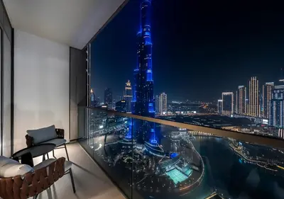 a room with a view of a city at night at Iconic Burj Khalifa & Fountain Views, Luxury 2BR Downtown in Dubai
