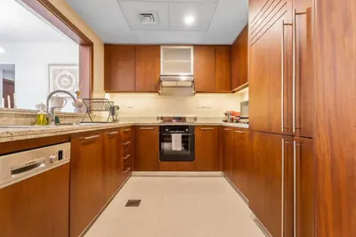 a kitchen with wooden cabinets and a stainless steel refrigerator at Boema Apartments- Luxury with Burj Khalifa View in Dubai