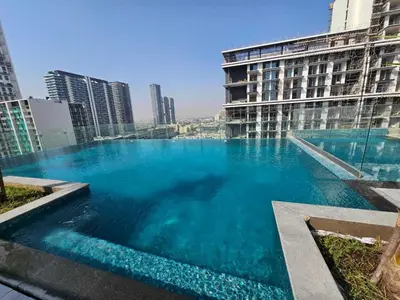 a large pool of blue water in front of a building at Beautiful Studio in Jumeirah Village Circle in Dubai