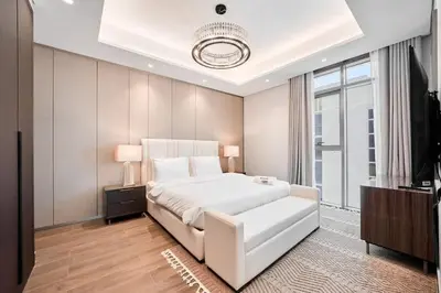 a bedroom with a large white bed and a television at FAM Living Stylish 1BR in Nobles Tower Near Downtown in Dubai