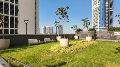 a park with benches and trees and buildings at FAM Living Stylish 1BR in Nobles Tower Near Downtown in Dubai