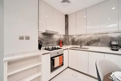 a white kitchen with a stove and a sink at FAM Living Stylish 1BR in Nobles Tower Near Downtown in Dubai