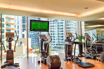 a gym with several treadmills and a flat screen tv at LUX The JW Marina Suite 4 in Dubai