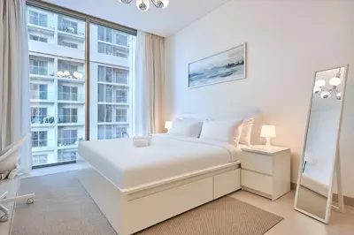 a white bedroom with a bed and a large window at STAY BY LATINEM Luxury 2BR Holiday Home CVR B405 Near Burj Khalifa in Dubai