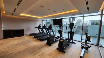 a gym with cardio equipment in a room with windows at STAY BY LATINEM Luxury 2BR Holiday Home CVR B405 Near Burj Khalifa in Dubai